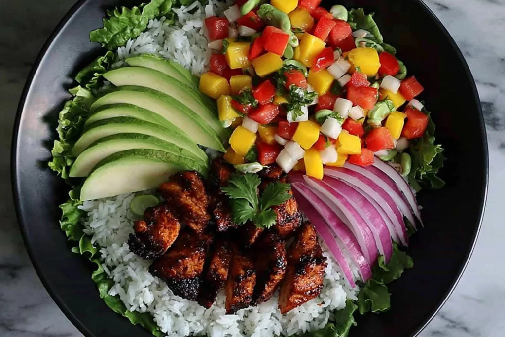 Jerk Chicken Buddha Bowl with Mango Salsa featuring grilled chicken, avocado slices, rice, and fresh colorful vegetables
