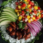 Jerk Chicken Buddha Bowl with Mango Salsa featuring grilled chicken, avocado slices, rice, and fresh colorful vegetables