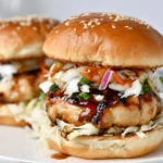 Chicken Teriyaki Burgers with glazed chicken patty, crunchy slaw, and sesame brioche bun on a white plate