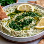 Creamy Lemon & Herb White Bean Dip topped with fresh herbs, olive oil, and lemon slices served with pita chips