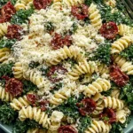 Mediterranean Pasta Salad with Kale featuring rotini pasta, sun-dried tomatoes, feta cheese, and creamy basil dressing in a serving bowl