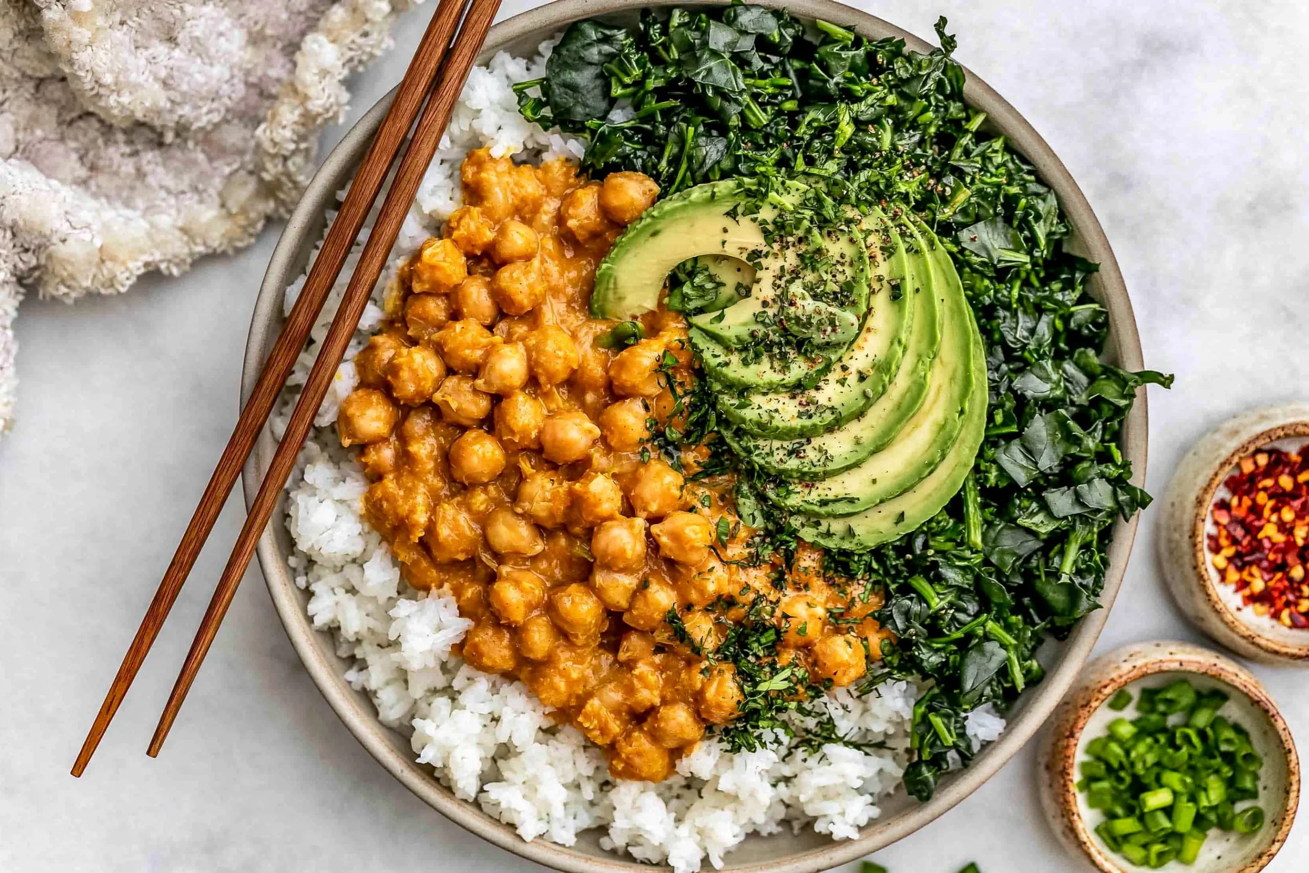 Peanut Chickpea & Veggie Bowls with creamy peanut sauce, rice, kale, and avocado slices in a healthy plant-based meal