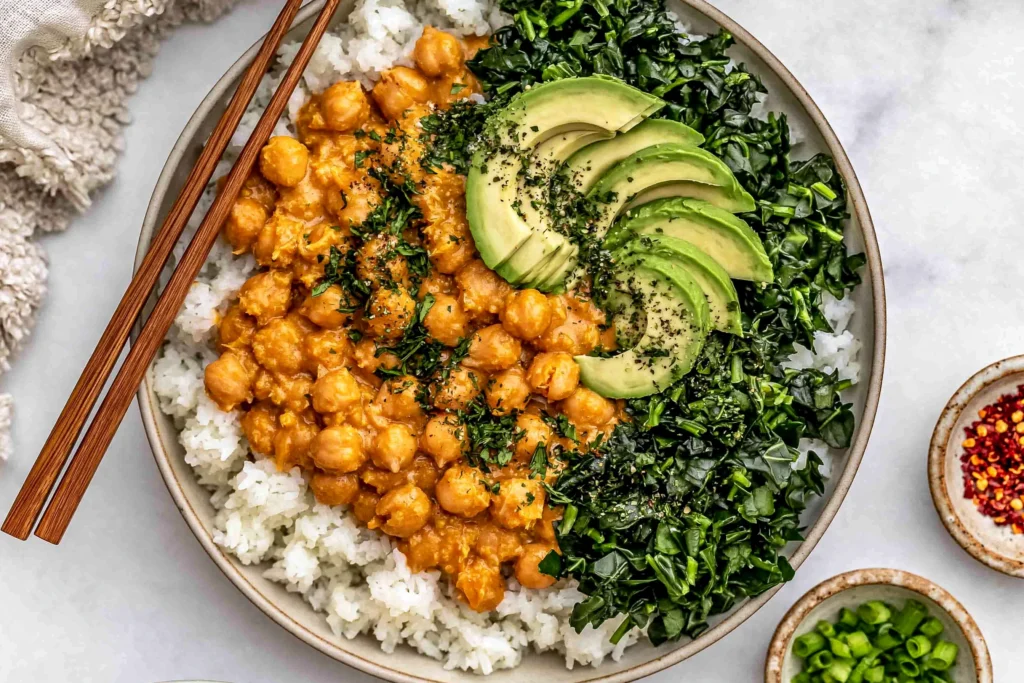 Peanut Chickpea & Veggie Bowls with creamy peanut chickpeas, jasmine rice, sautéed kale, and sliced avocado in a nourishing bowl