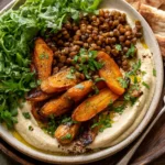 Roasted Carrot and Lentil Salad with Hummus served in a bowl with caramelized carrots, lentils, greens, and creamy hummus base