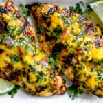 Grilled Mango Lime Chicken with juicy charred chicken breasts topped with mango lime sauce, fresh cilantro, and lime wedges
