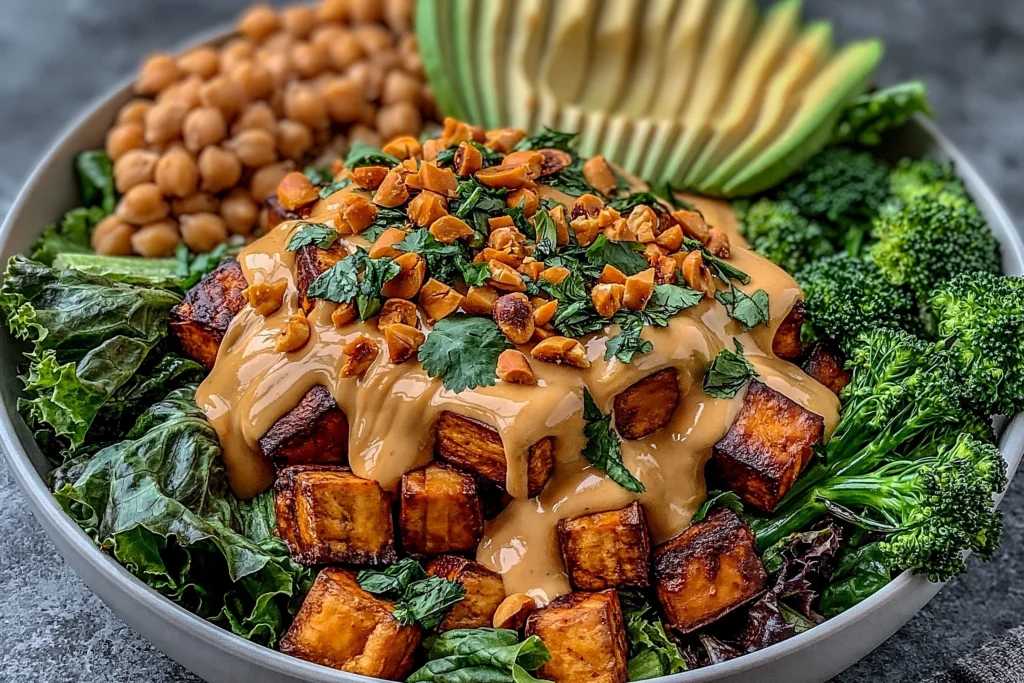 Thai Peanut Sweet Potato Buddha Bowl with roasted sweet potatoes, broccoli, avocado, chickpeas, and creamy peanut sauce topped with chopped peanuts and cilantro
