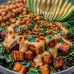 Thai Peanut Sweet Potato Buddha Bowl with roasted sweet potatoes, broccoli, avocado, chickpeas, and creamy peanut sauce topped with chopped peanuts and cilantro