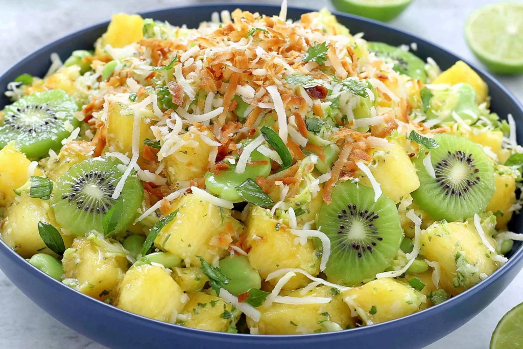 Pineapple Kiwi Salad with fresh mint, toasted coconut, and honey lime dressing in a vibrant tropical bowl