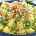 Pineapple Kiwi Salad with fresh mint, toasted coconut, and honey lime dressing in a vibrant tropical bowl