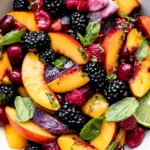 Honey Lime Basil Peach Fruit Salad with juicy peaches, blackberries, raspberries, basil, and fresh lime in a colorful summer bowl