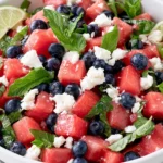 Watermelon Feta Salad served with blueberries, fresh basil, mint, feta cheese, and lime wedges