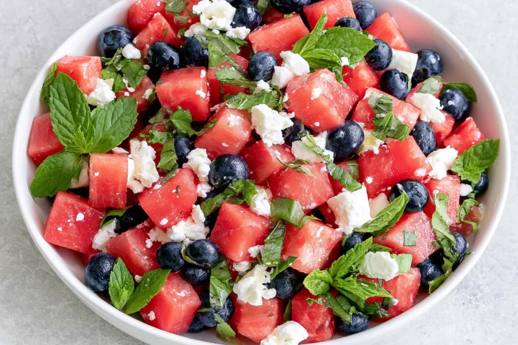 Watermelon Feta Salad with blueberries, fresh mint, basil, and crumbled feta in a serving bowl