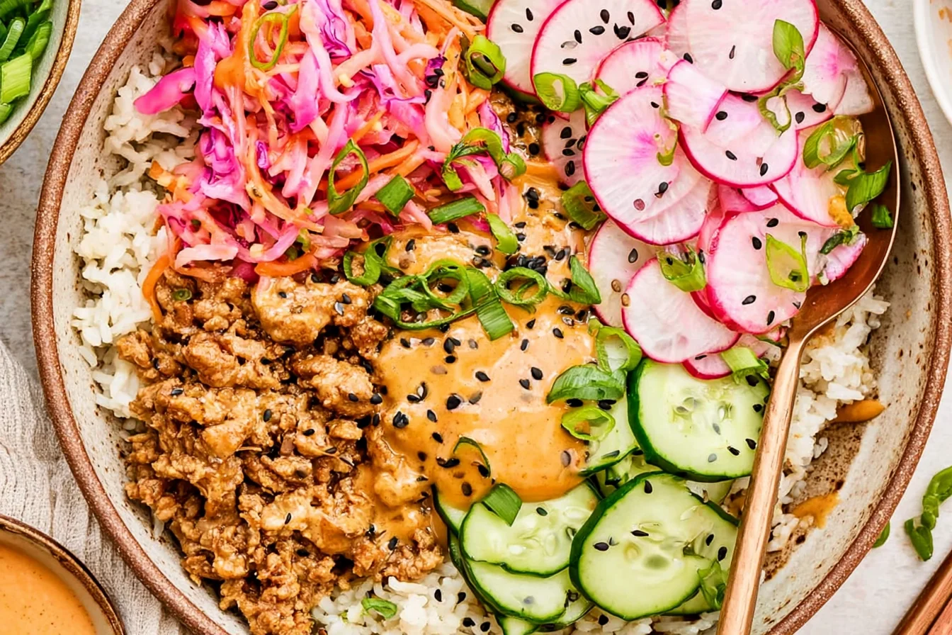 Ground Turkey Rice Bowls with bang bang sauce, fresh cucumbers, radishes, shredded cabbage, and sesame seeds over white rice