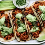 Black Bean Quinoa Tacos served with avocado slices, fresh cilantro, and creamy cilantro lime sauce on warm tortillas