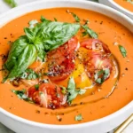 Easy Gazpacho Recipe topped with cherry tomatoes, cucumber, basil, and olive oil in a creamy chilled soup