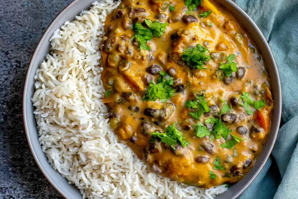 Creamy Black Bean Curry with coconut cream, black beans, fresh cilantro, and fluffy white rice in a bowl.