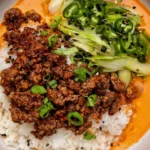 Crispy Ground Beef and Rice with creamy gochujang broth, jasmine rice, green vegetables, sliced peppers, scallions, and sesame seeds.