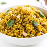 Coconut Curry Quinoa topped with fresh cilantro and sliced almonds in a white serving bowl.