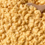 Creamy Cottage Cheese Mac and Cheese with elbow macaroni covered in a rich cheddar sauce and served with a wooden spoon.