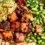 Honey Sriracha Salmon Bowls with glazed salmon, white rice, avocado, edamame, sesame seeds, and green onions.