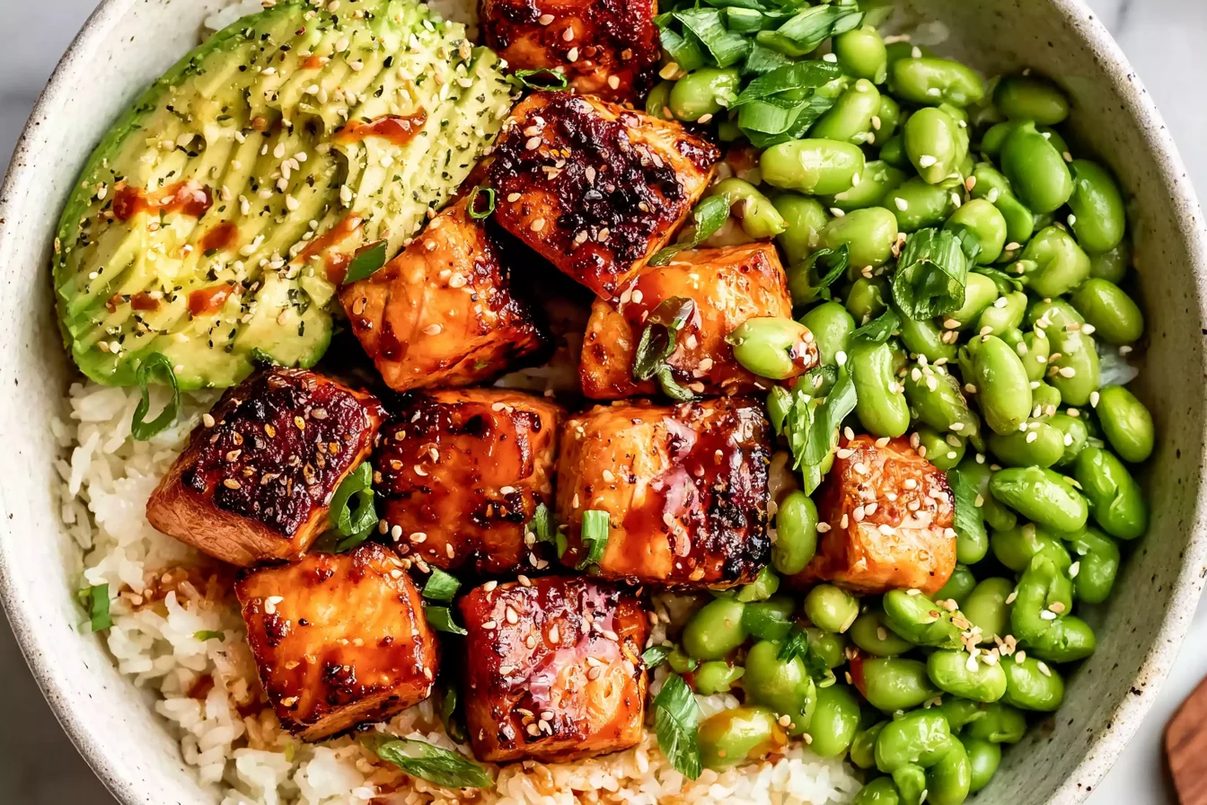 Honey Sriracha Salmon Bowls with glazed salmon, white rice, avocado, edamame, sesame seeds, and green onions.