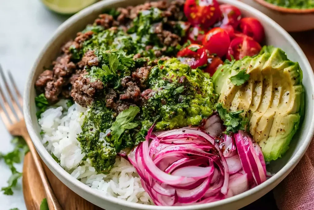 Ground Beef Chimichurri Bowls with rice, avocado, cherry tomatoes, and pickled red onions topped with fresh herb chimichurri sauce