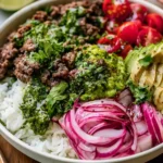 Ground Beef Chimichurri Bowls with rice, avocado, cherry tomatoes, and pickled red onions topped with fresh herb chimichurri sauce