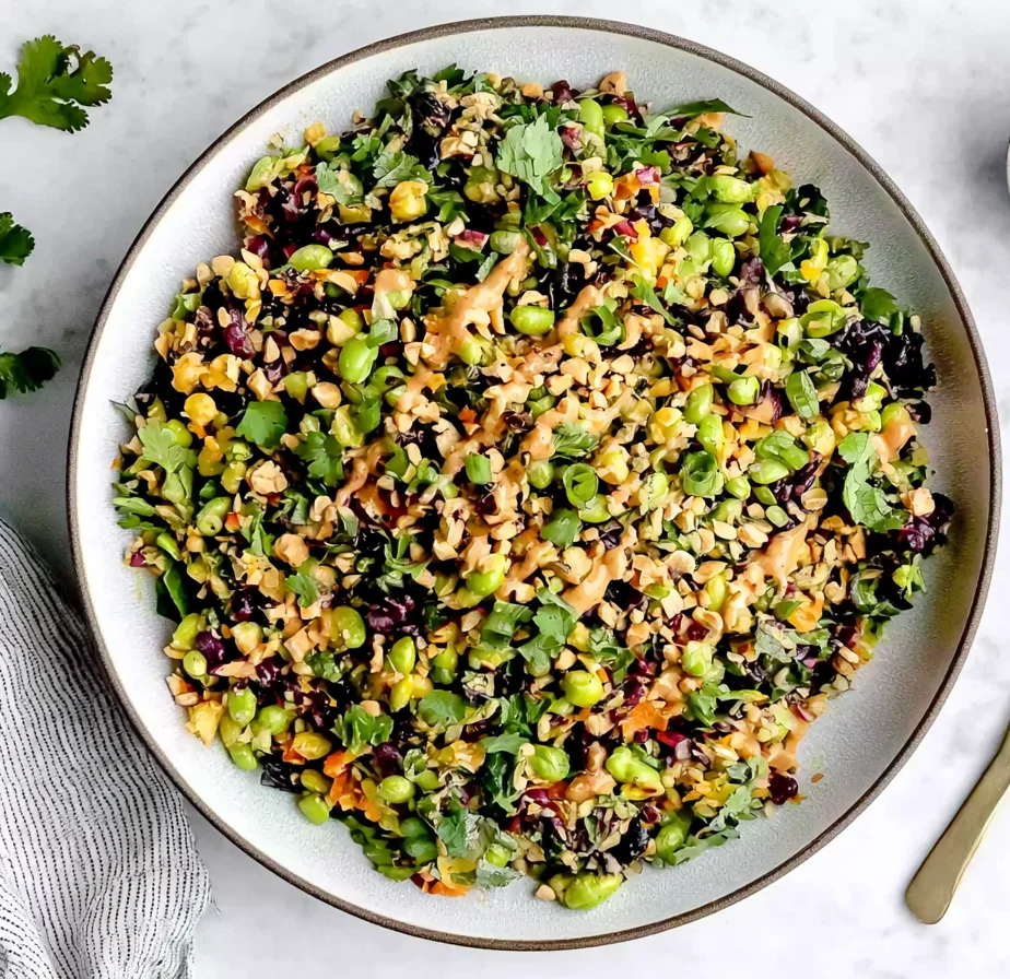 Colorful Edamame Peanut Crunch Salad with shredded cabbage, kale, carrots, and creamy peanut dressing topped with chopped nuts