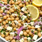 Lemony Chickpea Feta Salad with chickpeas, feta cheese, red onion, parsley, and fresh lemon slices in a bowl