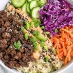 Korean Beef Bowl with ground beef, shredded carrots, red cabbage, cucumber, and spicy sauce over cauliflower rice