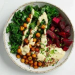 Quinoa Beet Bowls with kale, roasted chickpeas, and creamy tahini dressing in a healthy vibrant bowl