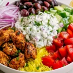 High-Protein Chicken Gyro Bowls with seasoned chicken, yellow rice, cucumber, tomatoes, red onion, Kalamata olives, and creamy tzatziki.