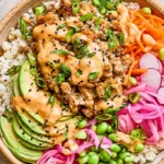 Ground Turkey Rice Bowls with creamy bang bang sauce, avocado slices, pickled onions, edamame, and fresh vegetables over rice