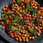 Mongolian Chickpeas stir fry with broccoli, bell peppers, and sesame seeds in a savory glossy sauce