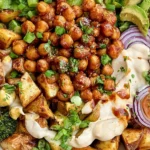 Roasted Potato Salad with BBQ Chickpeas topped with creamy tahini sauce, roasted broccoli, red onion, tomatoes, avocado, and fresh herbs.