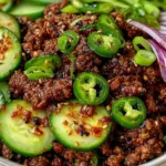 Spicy Korean Ground Beef with Cucumber Salad topped with jalapeños, sesame seeds, and red onions in a bowl