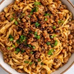Close-up of Honey Garlic Chicken Noodles with sticky sauce, ground chicken, sesame seeds, and green onions