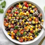 Sweet Corn and Black Bean Quinoa Salad served in a white bowl with quinoa, black beans, sweet corn, tomatoes, cilantro, red onion, and fresh lime