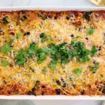 : Vegetarian Black Bean Quinoa Casserole baked with black beans, quinoa, tomatoes, melted cheese, and fresh cilantro in a white baking dish.