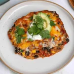 Vegetarian Black Bean Quinoa Casserole topped with melted cheese, avocado, fresh cilantro, and creamy sour cream.