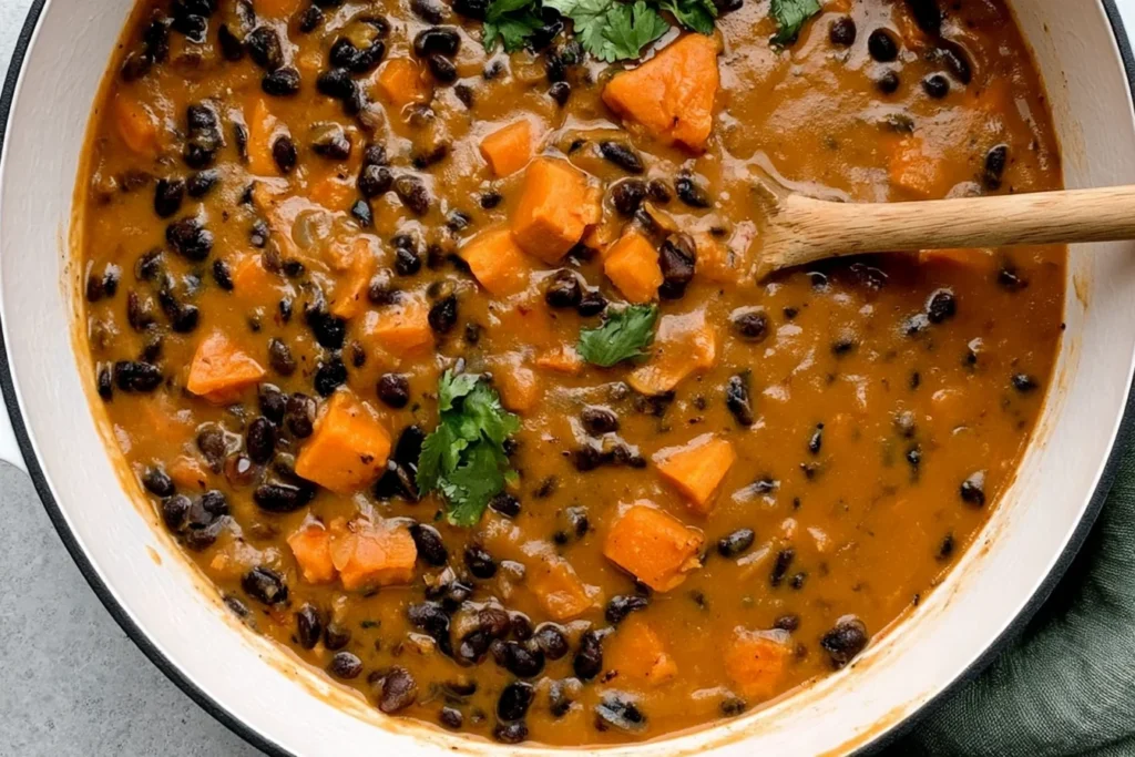 Chipotle Black Bean & Sweet Potato Soup simmering in a pot with black beans, tender sweet potato chunks, and fresh cilantro.