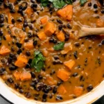 Chipotle Black Bean & Sweet Potato Soup simmering in a pot with black beans, tender sweet potato chunks, and fresh cilantro.