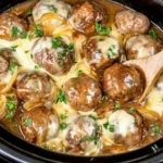 Crock Pot French Onion Meatballs with caramelized onions, savory gravy, melted Gruyere cheese, and fresh parsley.