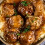 Crock Pot French Onion Meatballs served over creamy mashed potatoes with rich onion gravy and fresh parsley.