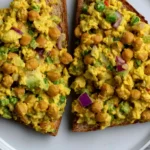 Crried Chickpea Salad served on toasted bread with chickpeas, red onion, green vegetables, and creamy golden curry dressing.