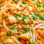 Chicken Pad Thai with tender chicken, rice noodles, bean sprouts, chopped peanuts, and fresh green onions.