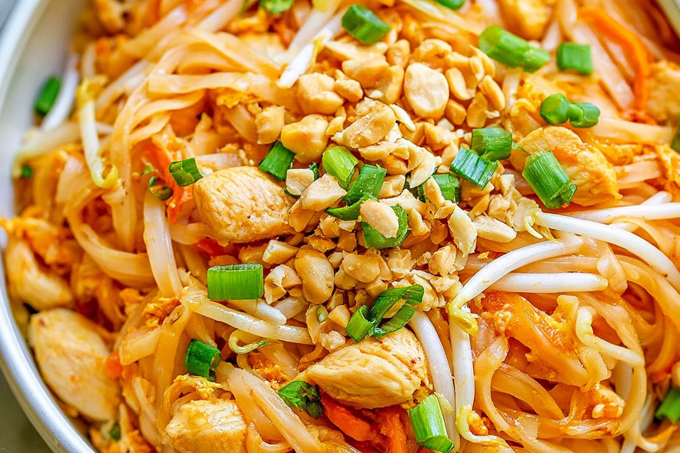 Chicken Pad Thai with tender chicken, rice noodles, bean sprouts, chopped peanuts, and fresh green onions.