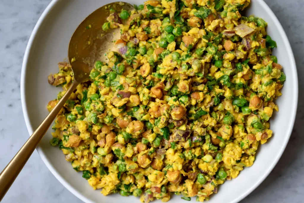Curried Chickpea Salad with creamy curry dressing, chickpeas, fresh herbs, red onion, and green vegetables in a white bowl.