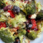 Mediterranean Broccoli Bake with roasted broccoli, Kalamata olives, red peppers, feta cheese, Parmesan, and herbs served on a white plate.