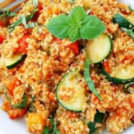 Tomato & Basil Quinoa Risotto with fresh tomatoes, zucchini, basil, and fluffy quinoa served in a white bowl.